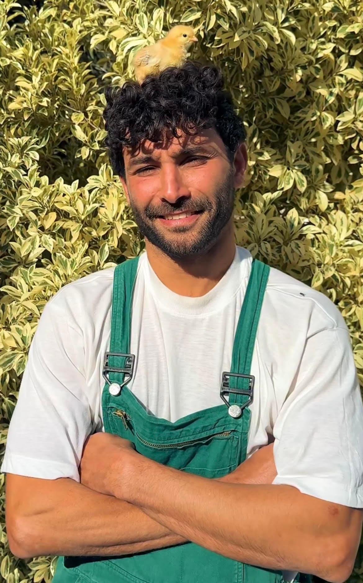 Mahdi sourit avec un poussin posé sur la tête à Farm El Baya